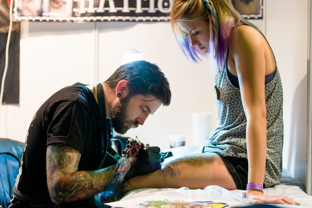 MINSK, BIELORUSSIA - 19 SETTEMBRE 2015 Tatuatore professionista che fa tatuaggio sul piede del cliente.