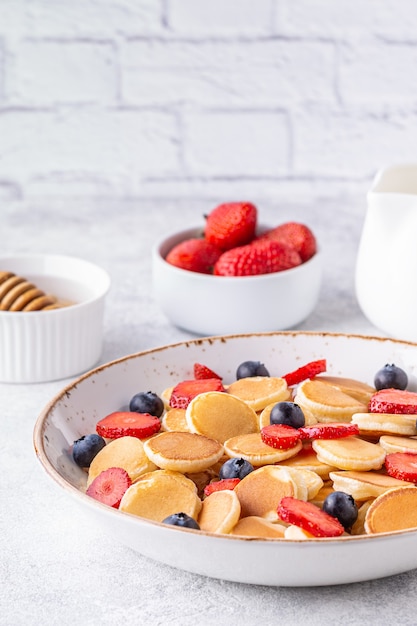 Minuscole frittelle con fragole e mirtilli per colazione. Messa a fuoco selettiva.