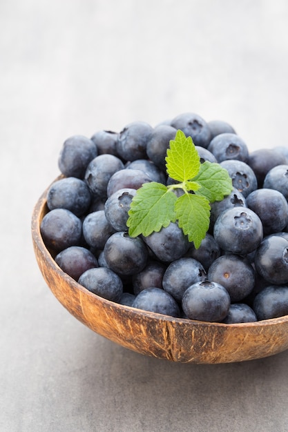 Mirtilli freschi cocco naturale in una ciotola su un grigio.