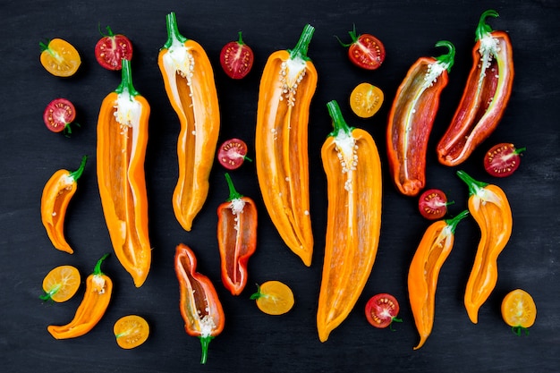 Misto di mezzo peperone rosso e giallo con un ramo verde vicino al pomodoro ciliegia