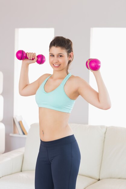 Misura i dumbbells castana della tenuta che sorride alla macchina fotografica