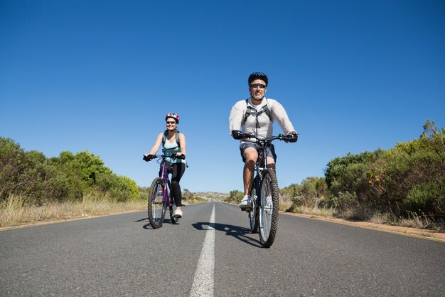 Misura le coppie sorridenti che vanno per un giro della bici nella campagna