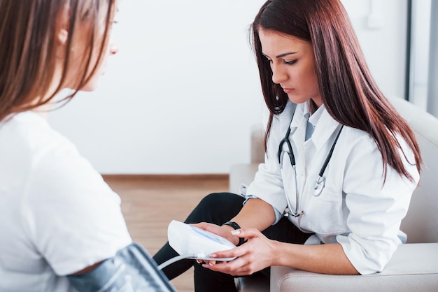 Misurazione della pressione sanguigna La giovane donna ha una visita con il medico femminile nella clinica moderna