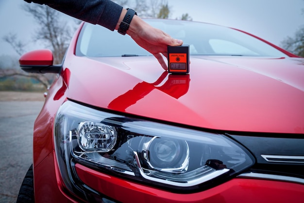 Misurazione dello spessore del rivestimento di vernice per auto di colore rosso utilizzando un misuratore di spessore della vernice.