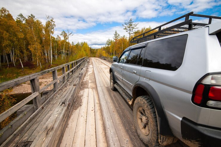 Mitsubishi Pajero Sport sul ponte di legno nella foresta autunnale