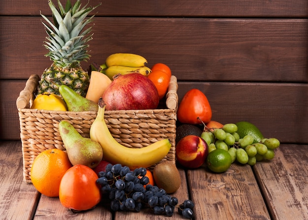 Mix di frutta tropicale esotica colorata fresca e succosa in cestino su fondo di legno