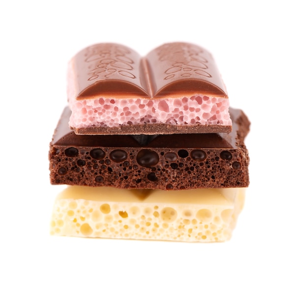 Mix di pezzi di cioccolato porosi isolati su sfondo bianco. Cioccolato aerato nero, bianco e rosa.