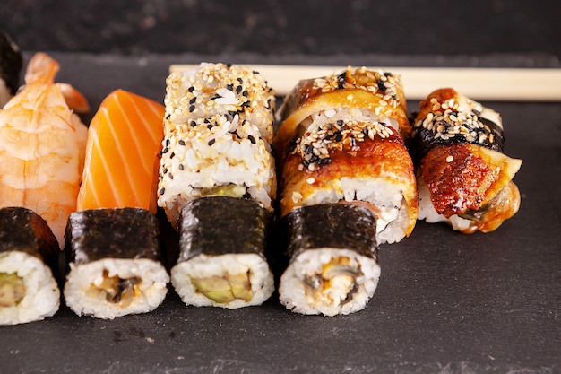 Mix di varietà di rotoli di sushi su sfondo nero in studio fotografico