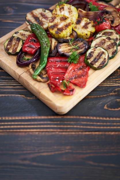 Mix di verdure grigliate su un tagliere di legno zucchine melanzane cipolle mais funghi pomodoro