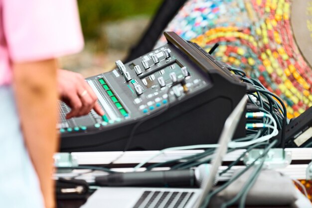 Mixer audio per la regolazione manuale del tecnico del suono al concerto dal vivo all'aperto, cursori e pulsanti sulla scrivania della console di missaggio audio. Mixer audio da palco professionale a portata di mano dell'ingegnere del suono utilizzando il cursore del mix audio