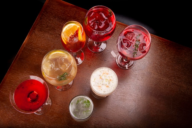 Mixology collezione di cocktail assortiti e colorati con tavolo e panca in legno vista dall'alto