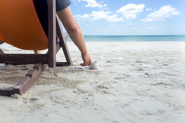 Mn seduto sulla sdraio e beve un caffè sulla spiaggia