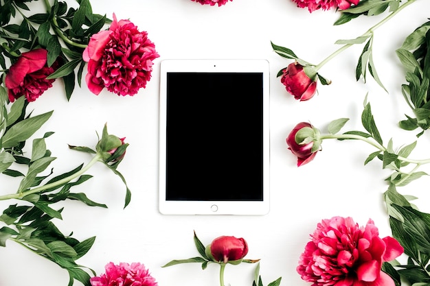 Mock up del telaio di fiori di tablet e peonie su superficie bianca