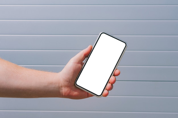 Mock up di uno smartphone nella mano di un uomo. sullo sfondo di un muro grigio.