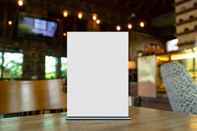 Mock up Etichetta la cornice del menu vuota nel bar ristorante. Supporto per opuscolo con carta acrilica in carta bianca sul tavolo con sfondo sfocato per inserire il testo o l'immagine