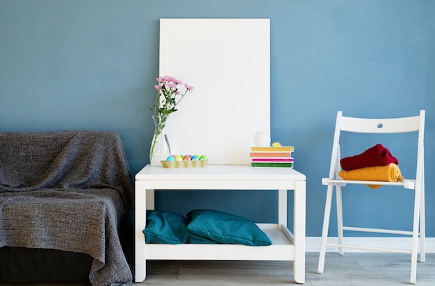 Mock up frame poster bianco sul tavolino in camera blu. Tela bianca bianca all'interno