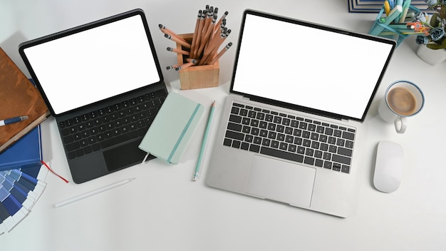 Mock up laptop computer tablet tazza di caffè portamatite e taccuino sulla scrivania bianca