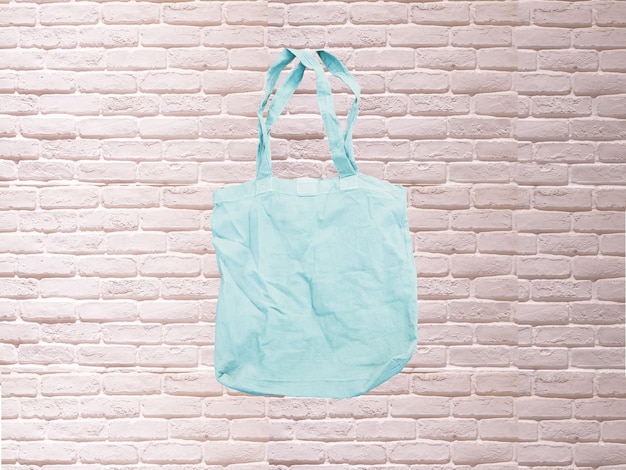 Mock up Tote bag eco hipster in tessuto di cotone bianco Shopping bag in blu. mattoni bianchi e tutto sfondo rustico