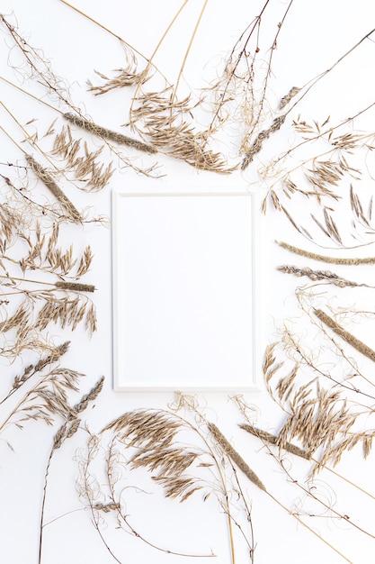 Mock up white photo frame flat lay with pampas grass on a white wall
