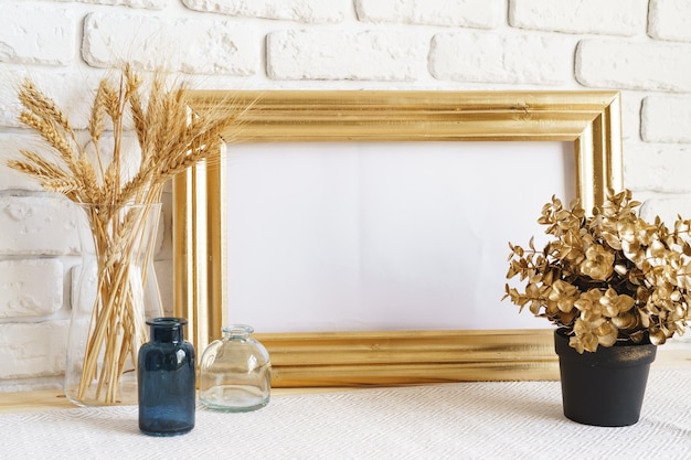 Mockup con cornice e fiori secchi in un vaso su un tavolo bianco