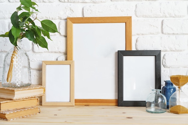 Mockup con cornice in legno sul tavolo con vaso moderno e libri