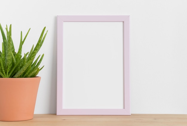 Mockup con cornice rosa con aloe vera in un vaso di ceramica su un tavolo di legno Orientamento verticale