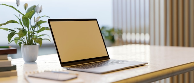 Mockup dello schermo di un laptop su una scrivania con decorazioni per la casa in uno spazio di lavoro moderno Ufficio interno 3d