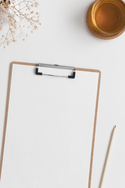 Mockup di appunti in legno con una tazza di tè e gypsophila su un tavolo bianco