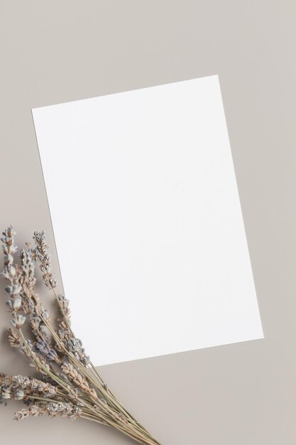 Mockup di biglietto d'invito bianco con lavanda essiccata su un tavolo beige con rapporto 5x7 simile ad A6 A5