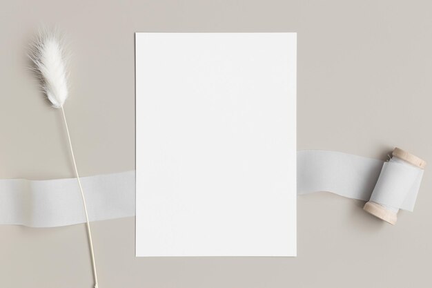 Mockup di biglietto d'invito bianco con un lagurus su un tavolo beige con rapporto 5x7 simile ad A6 A5