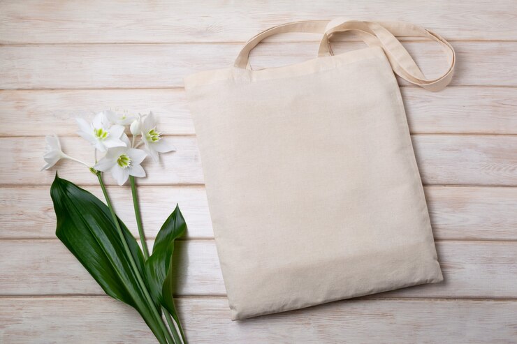 Mockup di borsa in tela con giglio bianco sul tavolo di legno