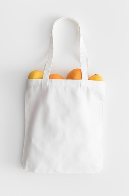 Mockup di borsa tote bianca con frutta su un tavolo bianco