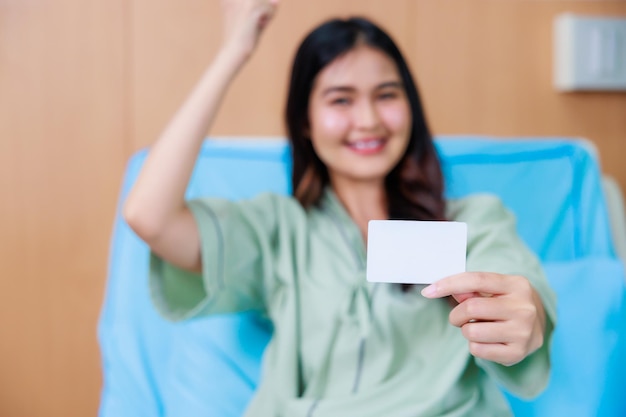 Mockup di carta bianca in asiatico Bella donna mano paziente seduta nel letto d'ospedale al centro medico