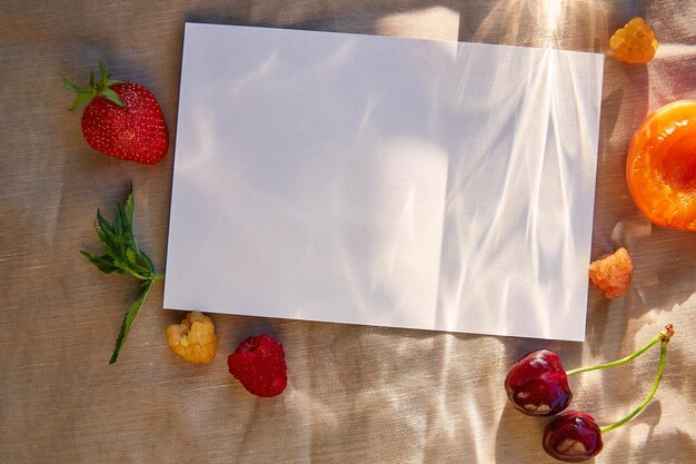 Mockup di carta di cancelleria estiva luminosa con ombre dure tra frutti di stagione e bacche Menu ricetta cartolina invito design piatto con spazio per la copia sotto la luce del sole