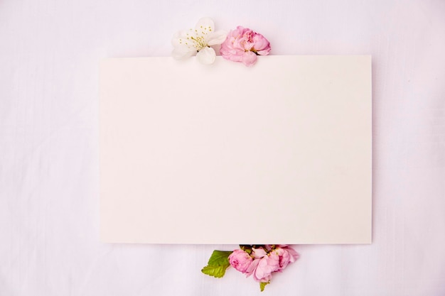 Mockup di carta di cancelleria femminile romantico con fiori bianchi e rosa primaverili Invito di compleanno di nozze festa della mamma mock up concetto di carta Spazio di copia Vista dall'alto