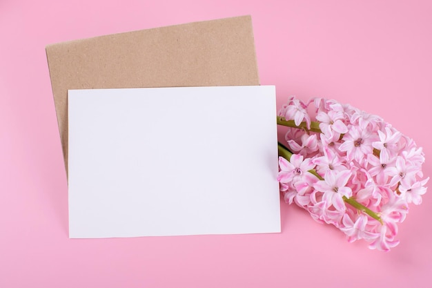 Mockup di carta di cancelleria per invito a nozze in bianco con busta su sfondo rosa con giacinto