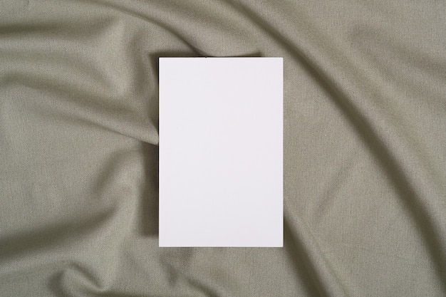 Mockup di carta di carta bianca bianca su tessuto di colore neutro verde
