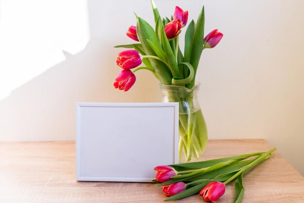 Mockup di cornice bianca ritratto su tavola di legno Vaso moderno con tulipaniInterni scandinavi