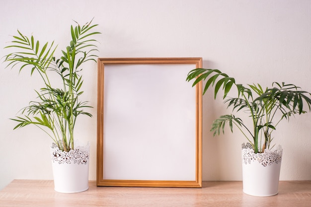 Mockup di cornice immagine ritratto broun sul tavolo di legno. Sfondo muro bianco. Interni scandinavi.