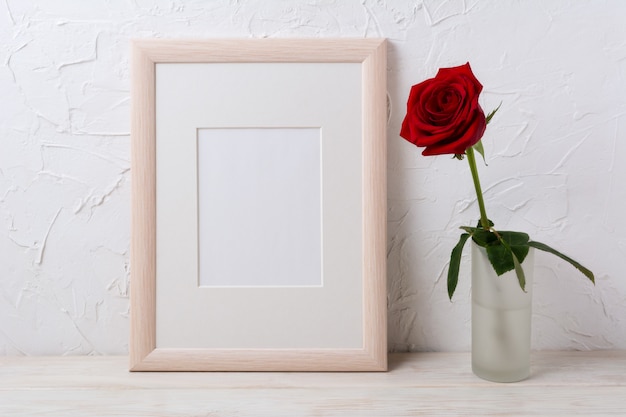 Mockup di cornice in legno con rosa rossa in vaso di vetro