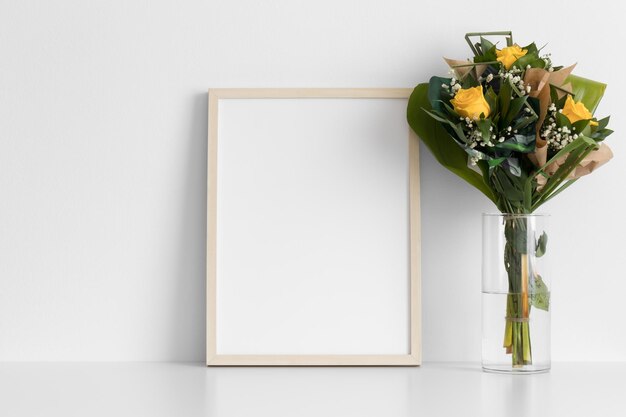 Mockup di cornice in legno con un mazzo di rose sul tavolo bianco