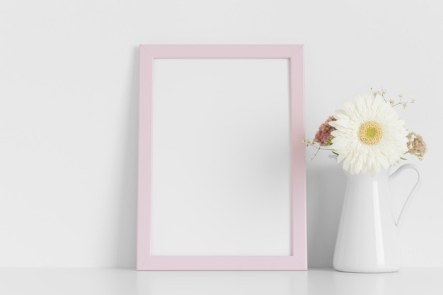 Mockup di cornice rosa con un mazzo di fiori sul tavolo bianco