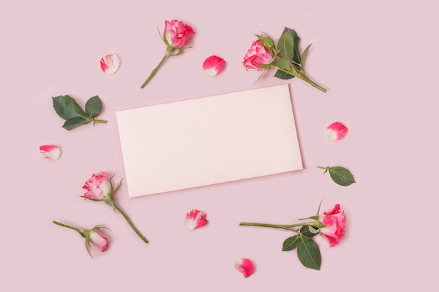 Mockup di invito o biglietto di auguri con un foglio bianco e alcune delicate rose rosa