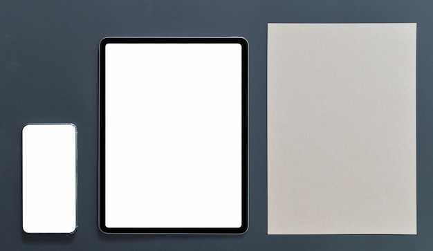 Mockup di smartphone con schermo vuoto del tablet e carta da nota marrone su sfondo nero