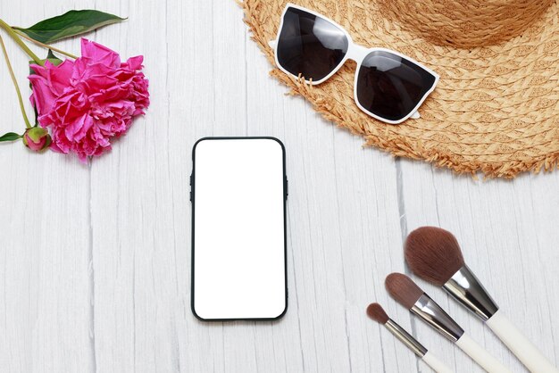 Mockup di smartphone su sfondo estivo con peonie e cappello di paglia in vacanza