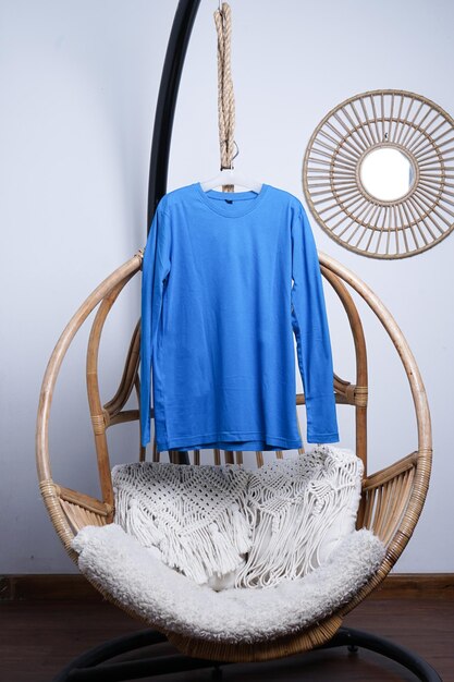 Mockup di t-shirt blu appeso su una sedia di legno su sfondo bianco