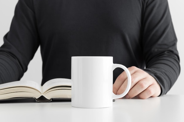 Mockup di tazza bianca con uomo che legge un libro