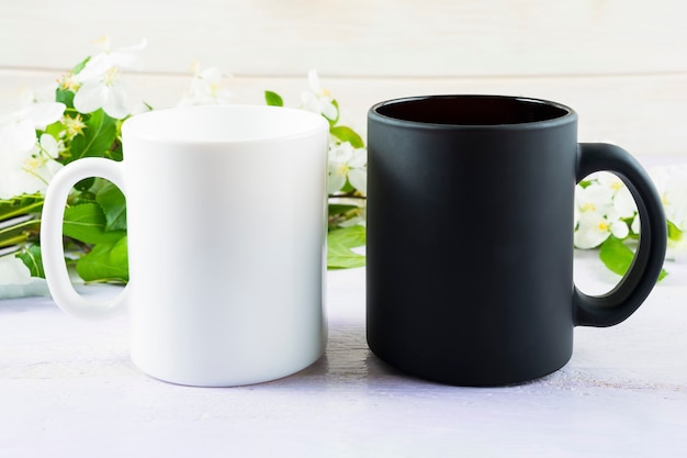 Mockup di tazza bianca e nera con fiori di melo primaverili