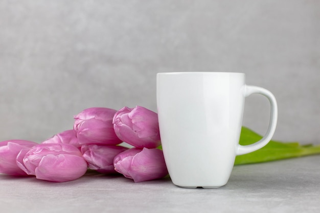 Mockup di tazza bianca vuota con tulipani rosa