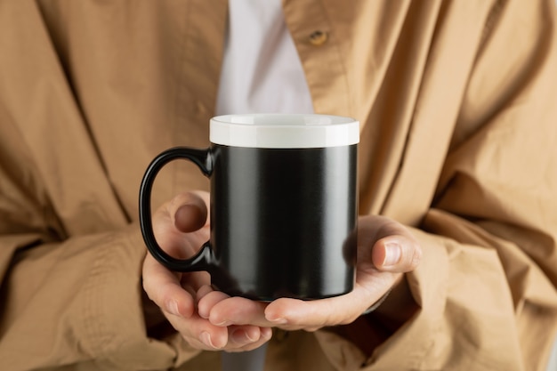 Mockup di tazza da caffè nero per dimostrazione di design elegante tazza mock up in mani femminili